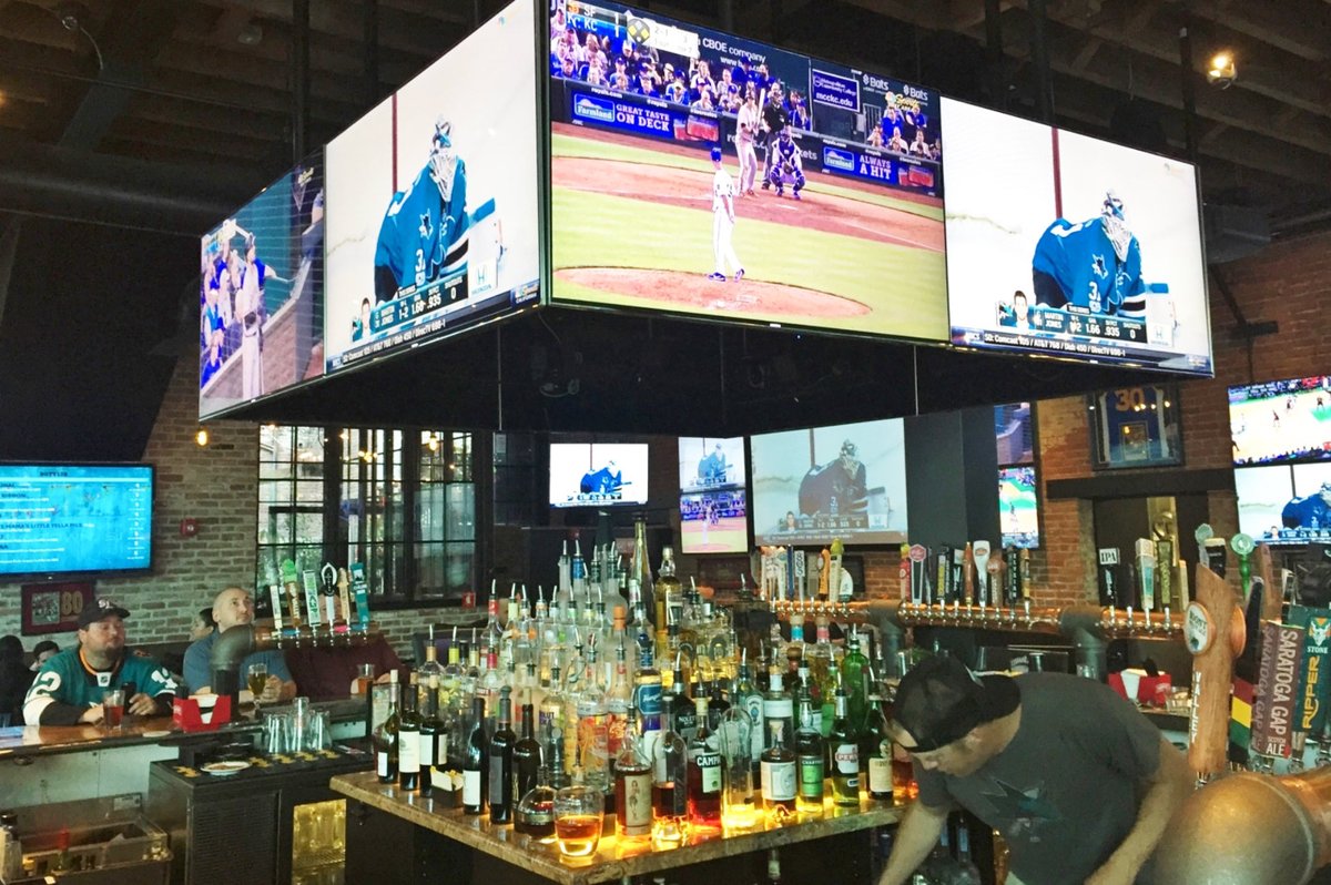 A bar with a large screen displaying a baseball game