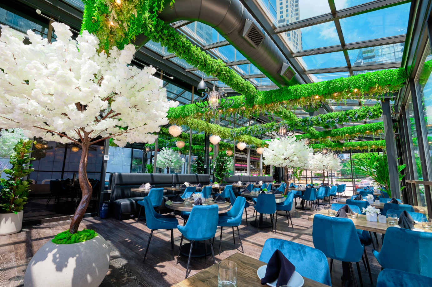 Sunlit glass covered patio with set tables, seating, and greenery decorations