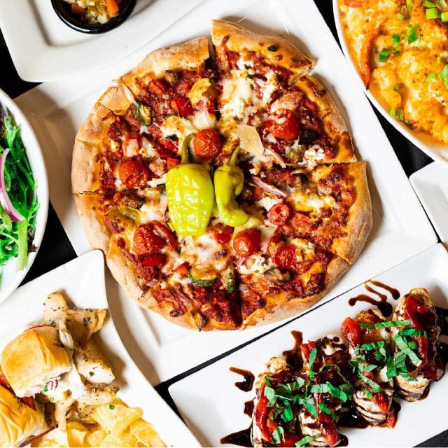 A variety of pizzas and appetizers on a table.