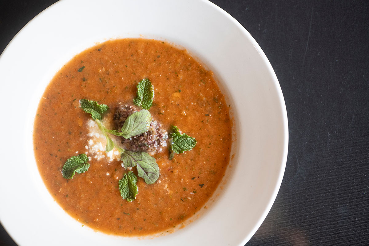 Overhead view of orange-red soup garnished with mint leaves