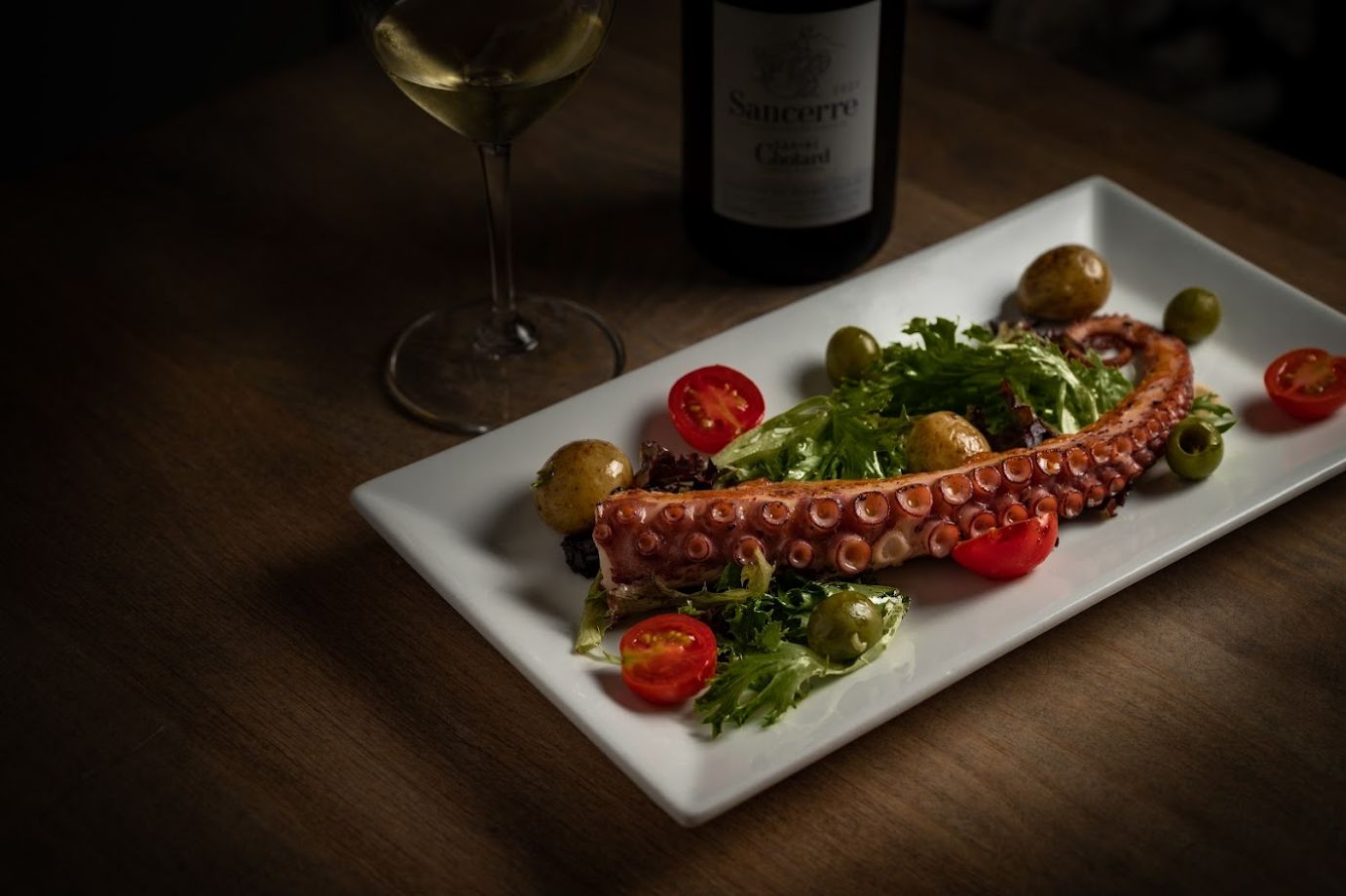 Grilled octopus with greens and cherry tomatoes