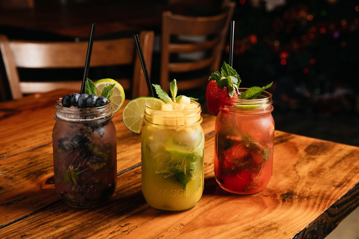 Three variants of Mojito cocktail, garnished and served in glass jars