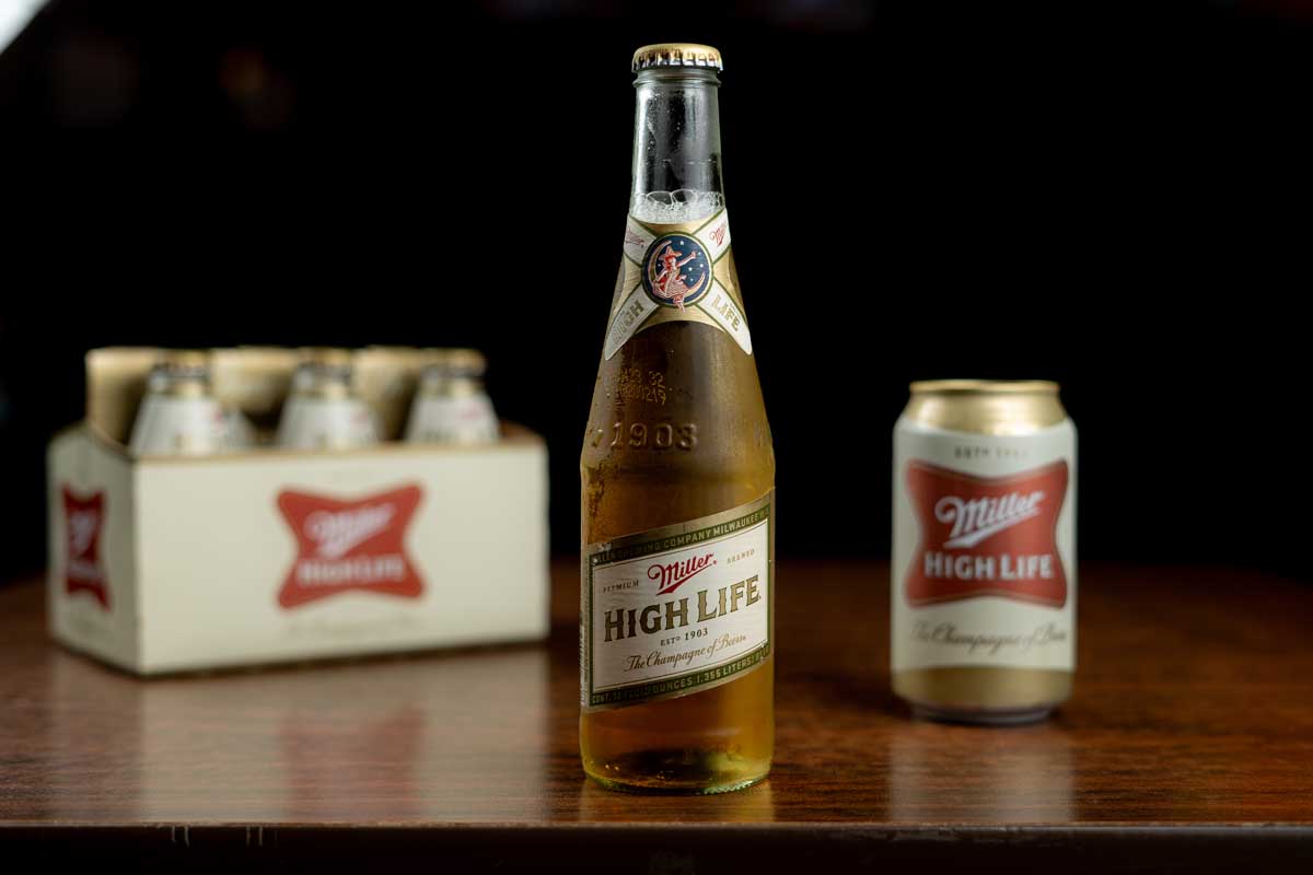Highlife Miller beer bottle, can and six-pack on the wooden table
