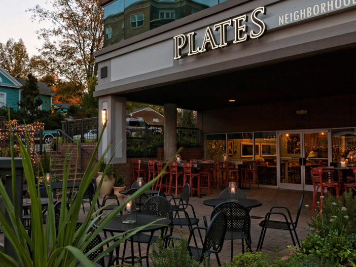 A restaurant with tables and chairs outside at dusk.