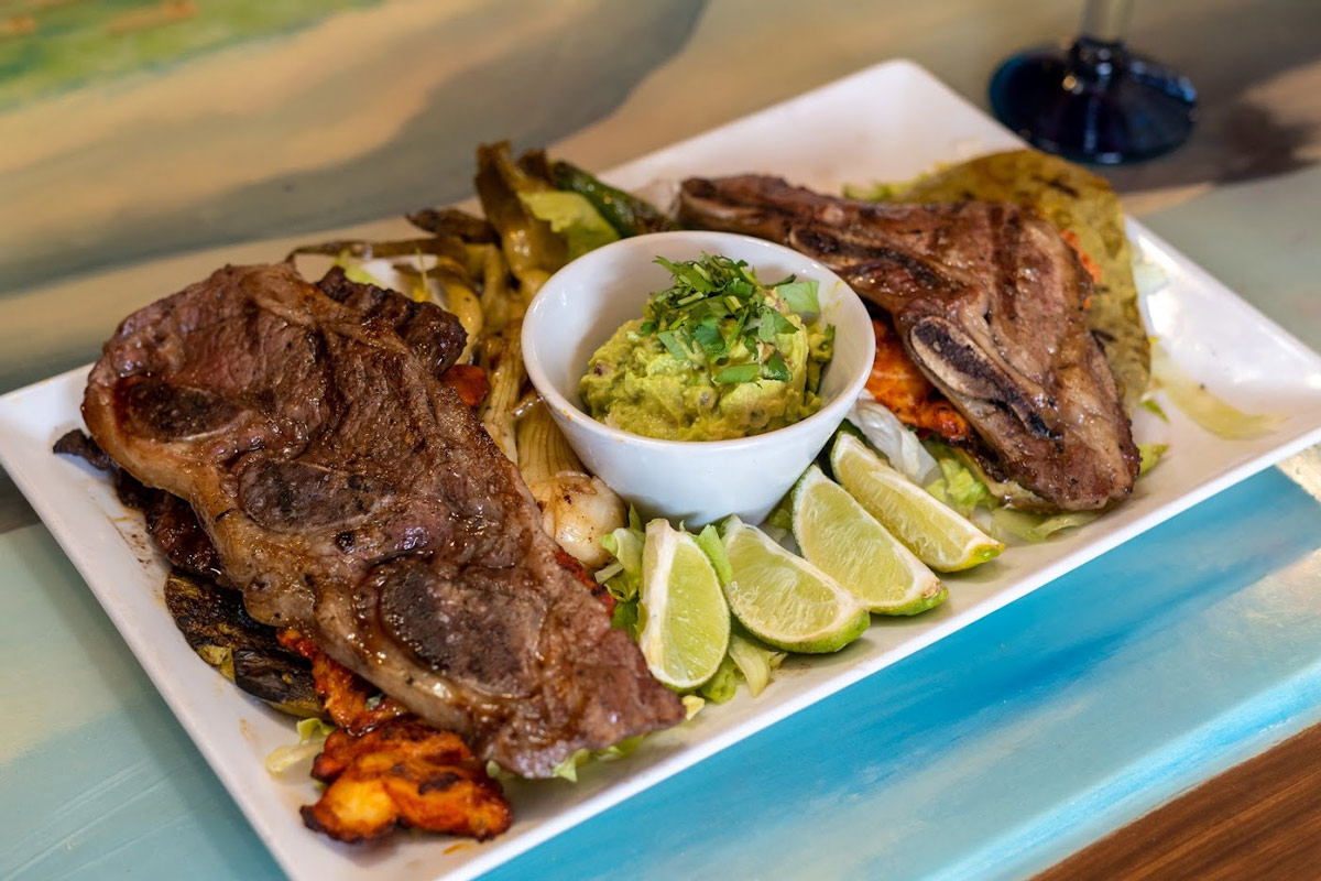 Grilled ribs with grilled vegetables, side of guacamole and lime wedges