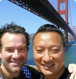 Two men smiling and posing for a photo in front of the iconic Golden Gate Bridge.