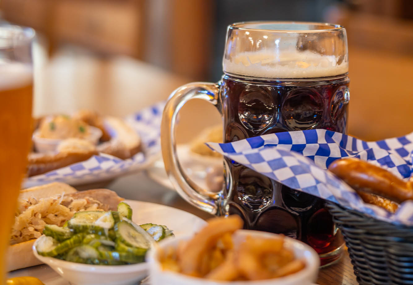 A table with a glass of beer, surrounded by food.