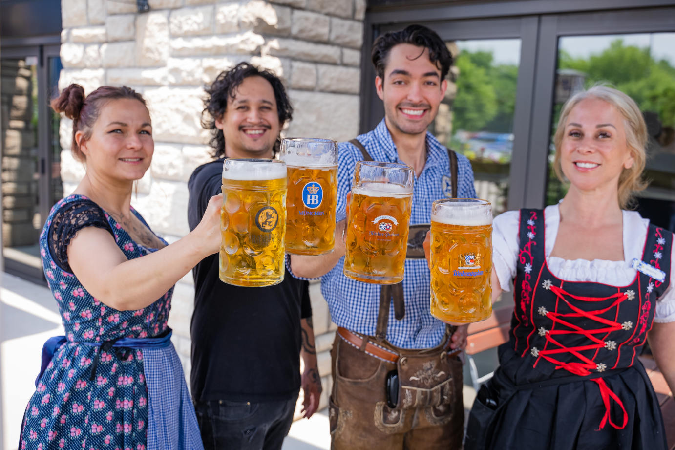 Four people holding glasses of beer
