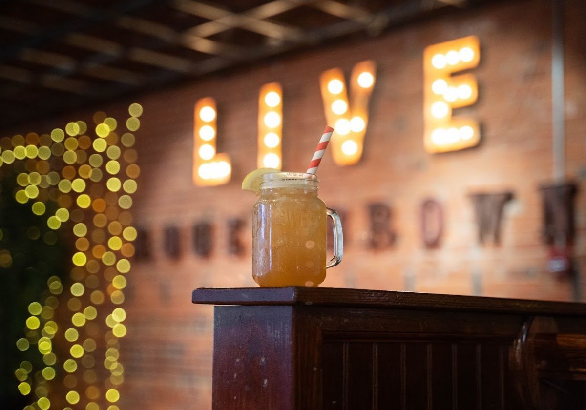 peach drink in front of a blured light sign on a wall