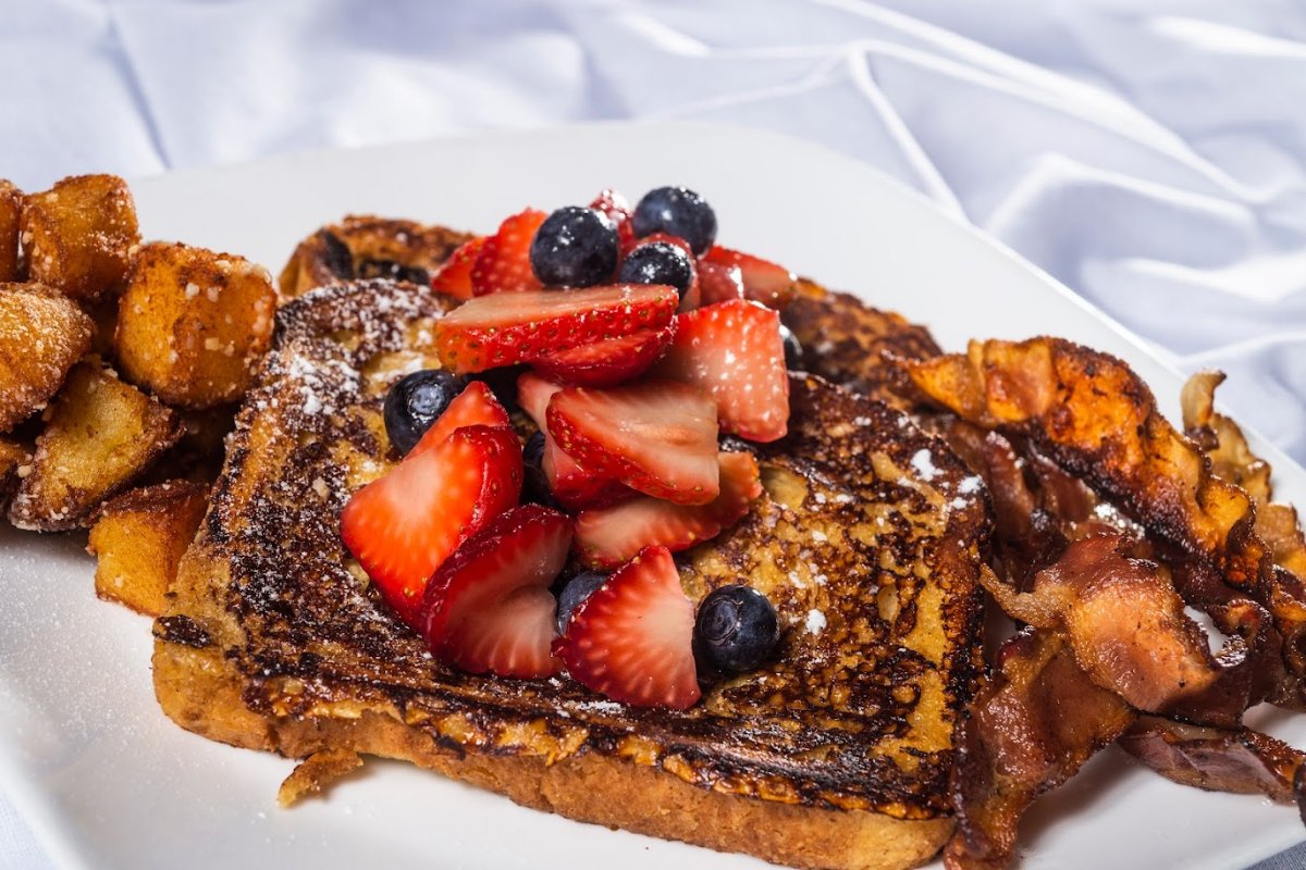 Close up of French toast with berries, bacon and roast potatoes