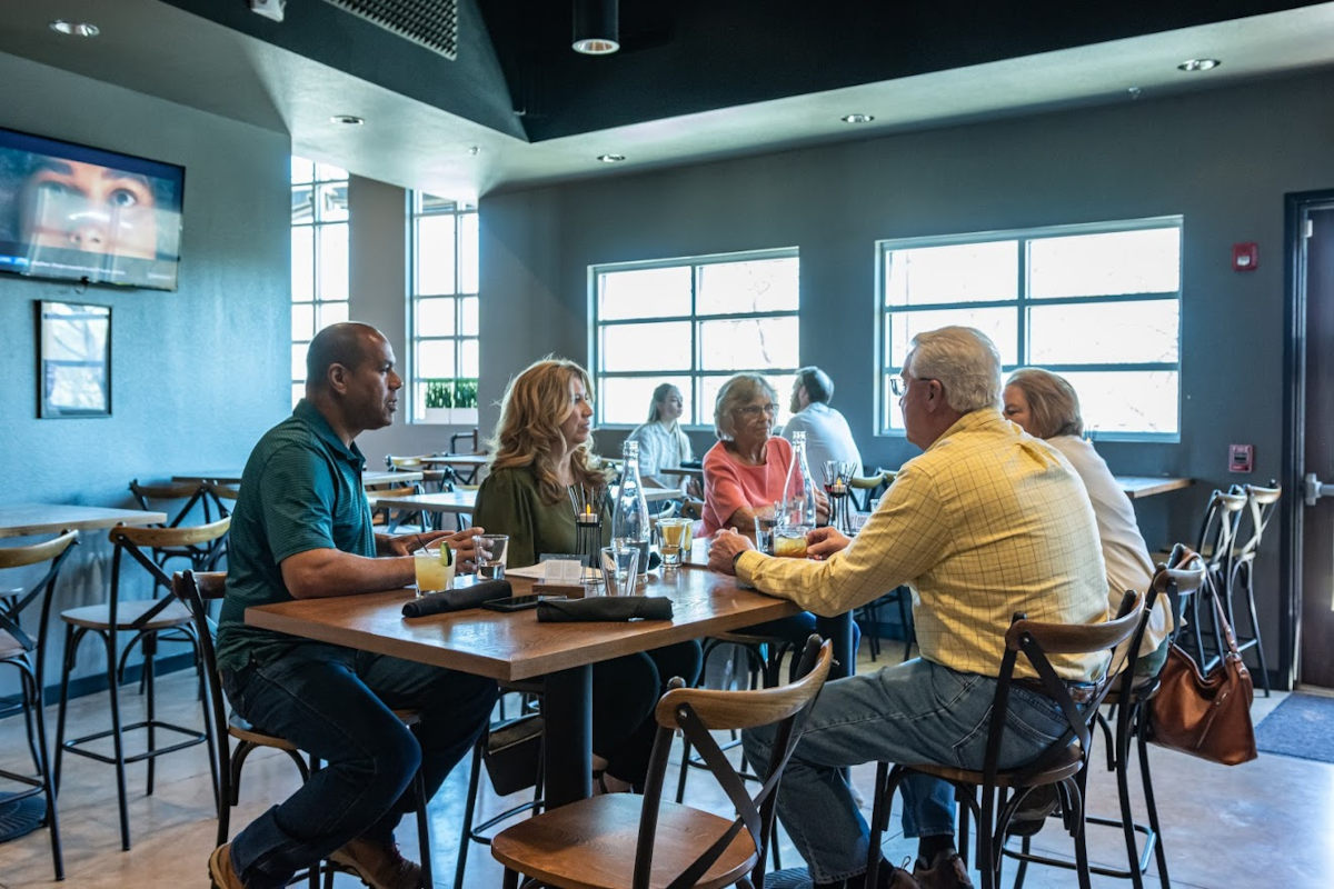 Interior, guests sitting at a table, chatting and enjoying drinks