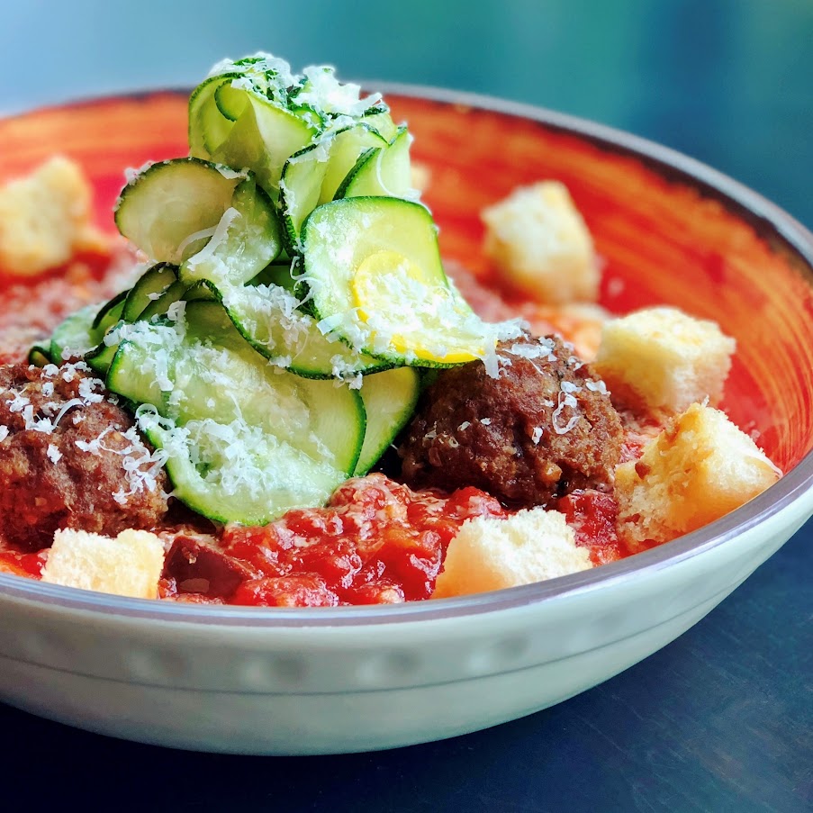 Meatballs in tomato sauce, with sliced cucumber, sprinkled cheese and croutons