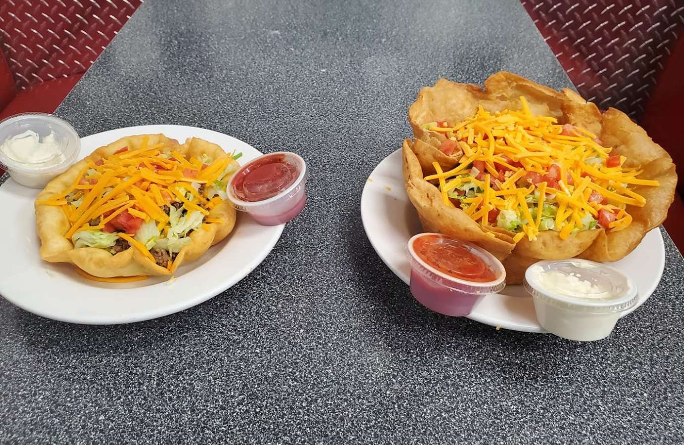 Two plates of tacos with sauces on a table