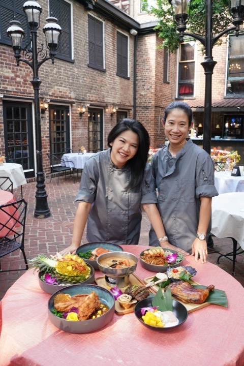 Two staff members standing by a table with food in the patio