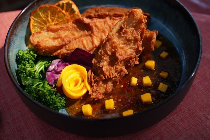 Fried fish served with broccolini, mango and citrus garnish
