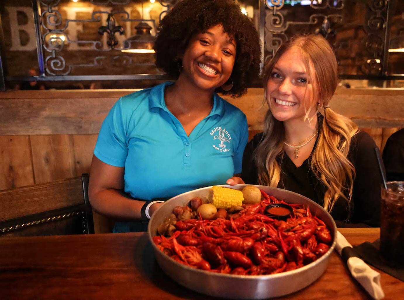 Two employees posing for a photo with the crawfish potato sorn sausage plate