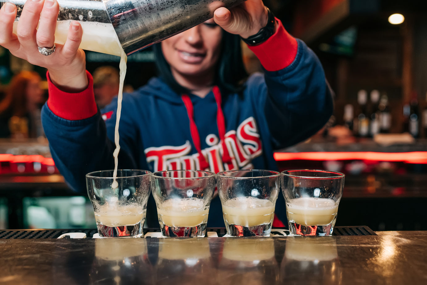 Bartender behind the counter pouring cocktail into glasses